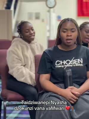 The cover image shows three young women seated in what appears to be a church or religious setting. The woman in the center is the primary focus of the image. She is wearing a black t-shirt with the word "CHOSEN", a water bottle in her hands, and is speaking. The woman sitting in the back on the left side and another woman sitting on the right side are partially visible. The background consists of the interior of the building with some chairs and a clock. The overall tone of the image is one of religious devotion.