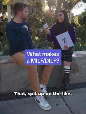 A man and a woman are on a street. The man is sitting on a low wall, and the woman is standing to the man's right, holding a microphone. A text overlay with the questions appears in the center of the screen.