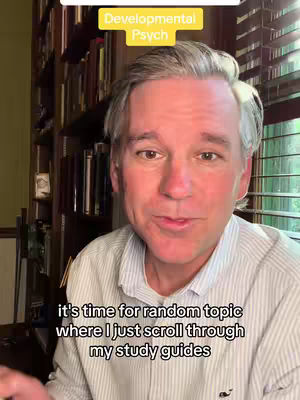 A man with gray hair and a light blue striped shirt stands in front of a bookshelf. He is looking directly at the camera, and yellow text boxes are overlaid on the image that say, “Developmental Psych” and text at the bottom of the image says, “it’s time for random topic where I just scroll through my study guides”.