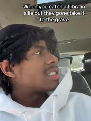 A young man is seated inside a car, his head turned toward the viewer. He's wearing a white hooded sweatshirt and a black head covering. Text overlays the top of the image.