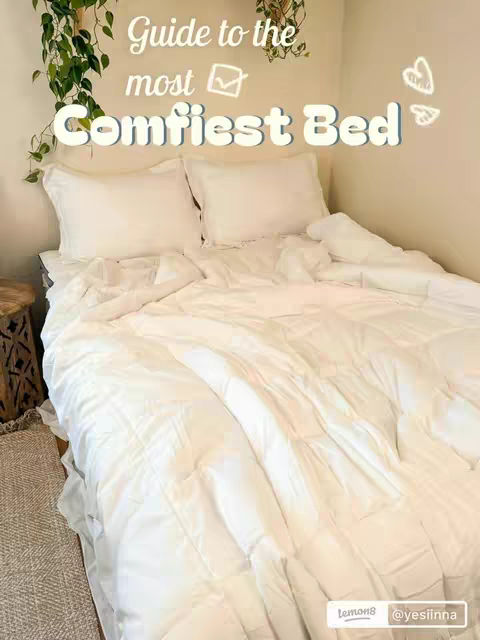 A well-made bed is the central focus, featuring a fluffy white comforter and pillows. The bed is in a corner, with a section of a wooden side table and a patterned floor rug visible. Text overlays highlight the video's focus.