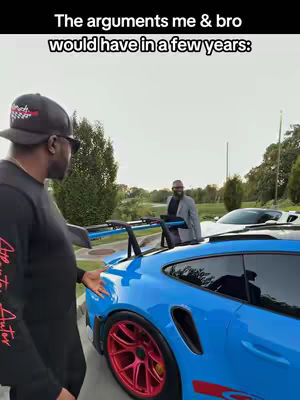 The image shows two men standing near a sports car. One man is closer to the camera, turned towards the vehicle, wearing a black long-sleeve shirt, sunglasses, and a baseball cap. The other man is standing further away, looking ahead and to the right, and appears to be wearing a blazer. The car is a bright blue sports car with red rims. Text overlays the image towards the top in bold white font.