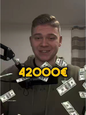 A young man with short brown hair smiles at the camera with money falling around him. The text overlay reads '42000€'. Behind him is a neutral background.