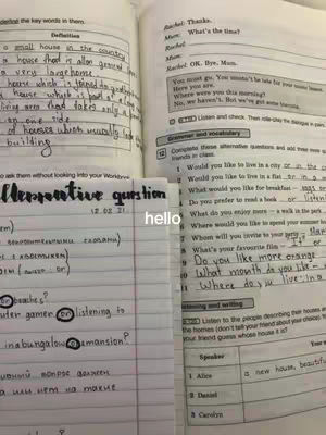 The image shows open books and notes with handwriting, likely related to English language study. The layout is cluttered with stacked pages and handwritten annotations. Colors are muted, focusing on the text content.