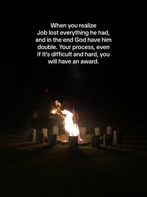 The image shows a nighttime scene with a campfire at the center. Around the fire, there are multiple blocks, likely logs or stones, arranged in a circle. Above this, text overlays provide context. Flames of fire are very vivid.
