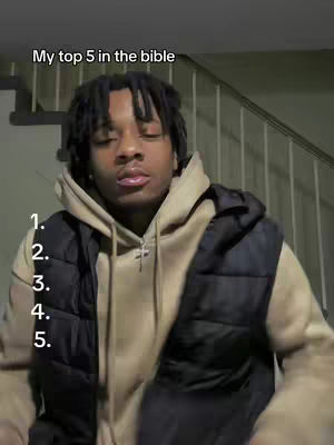 A young man with dreadlocks, wearing a hoodie under a black vest, is the central focus, while he is positioned against a backdrop of stairs and a neutral wall. The image is marked with the overlay text: "My top 5 in the bible" at top, with a numbered list descending the left side.