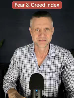 A man with short hair and a checked shirt sits in front of a dark background, a microphone is visible at the bottom of the frame, and there is a red bar at the top left with white text that says 'Fear & Greed Index'.