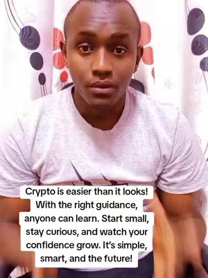 A man with dark skin and short hair looks directly at the camera. He is wearing a light grey t-shirt, and behind him are patterned curtains. Text overlayed on the image provides motivational advice about cryptocurrency.