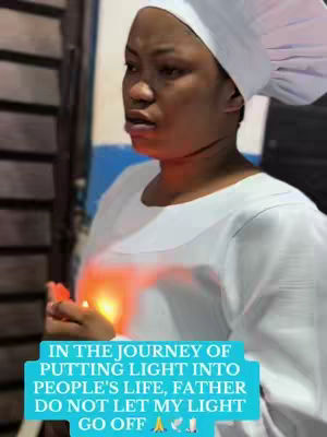 A woman wearing a white head covering and dress holds a lit candle in her hands. She has a concerned expression and is looking slightly off-camera. A light blue rectangular box with white text overlay is at the bottom of the image.