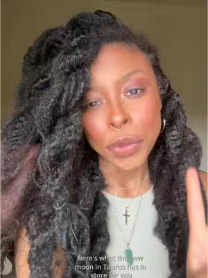 A close-up shot of a woman looking towards the camera with an expression, hair draped over her shoulders. The background is softly lit.