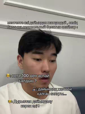 A young man of Asian descent is centered in a selfie-style shot. He has short, dark hair and is facing forward with a slightly concerned expression. The background is simple, with a glimpse of a white wall and a dark-colored surface, suggesting an indoor setting.