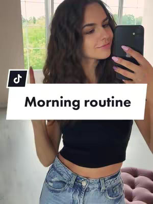 A woman holding a phone in front of a mirror. She is smiling.