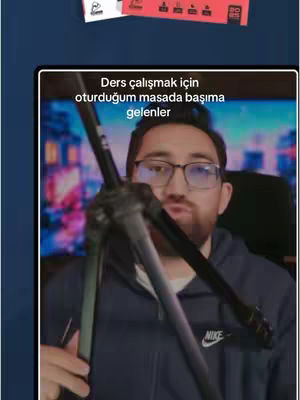 A man with glasses holds a tripod in front of him with text overlay on the image.