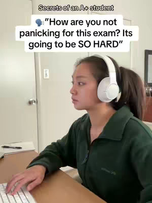 The cover image shows a young woman seated at a desk, typing on a keyboard. She's wearing over-ear headphones. A text overlay at the top says: "Secrets of an A+ student" followed by a speech bubble with the text: "How are you not panicking for this exam? Its going to be SO HARD". The background includes a door and wall.