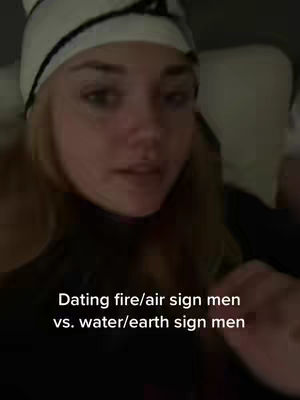 A young woman with long blonde hair wearing a white and black knit hat is shown in a close-up shot, likely in bed. Text at the bottom reads, "Dating fire/air sign men vs. water/earth sign men."