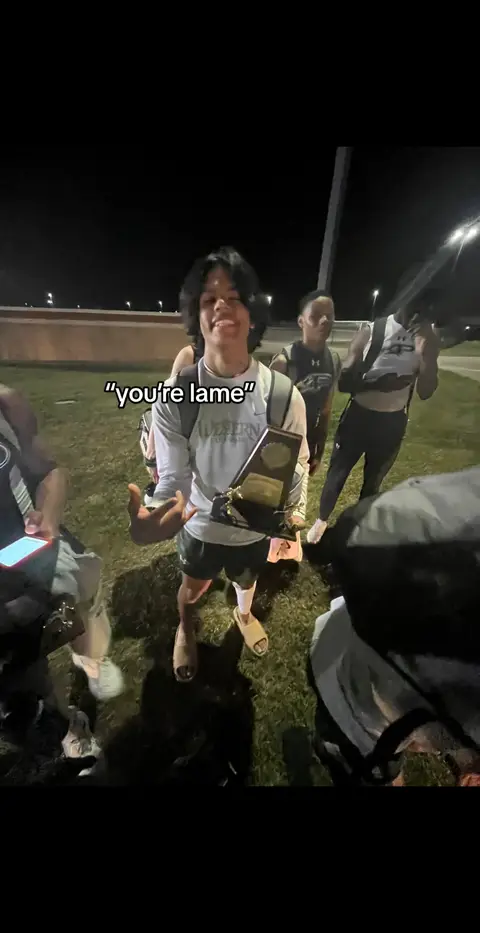 The cover image shows a group of people at what appears to be an outdoor event at night. In the center, a young man is holding a trophy and pointing towards the camera while smiling. Text overlayed on the image says "you're lame". Other people can be seen in the background.