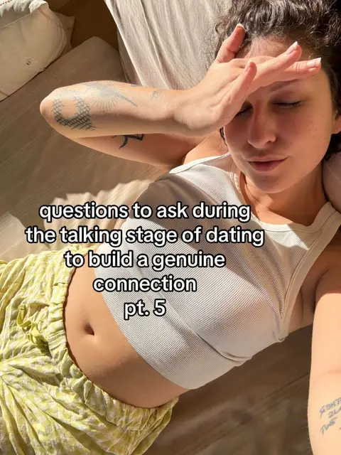 A woman lies on a bed, angled from the upper body, with her forehead resting on her hand. The background is a plain, neutral color. The woman wears a white tank top and patterned yellow-green pants. Text overlays the image, along the bottom of the image.