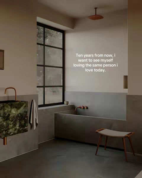 A minimalist bathroom setting with a large window as the primary light source. The space features concrete walls, dark flooring, and a modern bathtub. Text is overlaid on the image.