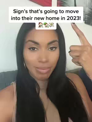 A woman with long black hair is centered in the frame, looking directly at the camera. Above her head is a rectangular white box with text, and a finger points at the text. The woman is wearing a light-colored top, and a hand is visible in the upper right corner. The background is blurred.