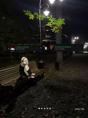 An anime-style illustration of a girl with white hair wearing headphones is sitting on a bench in a park at night. The scene includes a lamppost, trees, and the interface of a social platform with some song information on it. Overall, the image presents a moody, atmospheric setting.