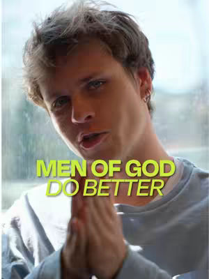 A young man with light skin is centered, shot from the chest up. He has short, light brown hair and is wearing a light gray long-sleeve shirt. His hands are clasped together in front of him, as if in prayer, and he’s looking towards the viewer with a slight smile. The background is out of focus, with a window visible on the right side. Overlaid on the image is green text: “MEN OF GOD DO BETTER”.