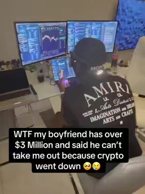 The cover image shows a person sitting in front of multiple computer monitors displaying financial data. They are wearing a black shirt with white lettering reading 'AMIRI'. The individual appears to be in an office setting, and a text overlay at the bottom of the image says 'WTF my boyfriend has over $3 Million and said he can't take me out because crypto went down'.