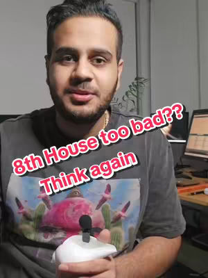 A man with a beard and dark hair is the central focus, wearing a gray t-shirt with a colorful graphic. The image has text overlays in a playful font, and a small microphone is attached to a white object.