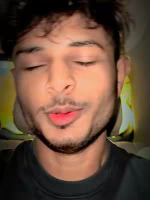 A close-up shot of a man with his eyes closed, lips slightly parted and red, potentially speaking. His hair is slightly unkempt, and he appears to be in a casual setting. The background is blurred.