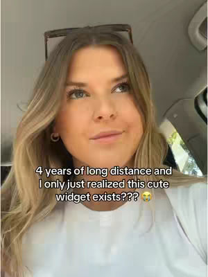 A woman with long blonde hair looks up slightly while sitting in a car. Text overlayed on image states: "4 years of long distance and I only just realized this cute widget exists???"