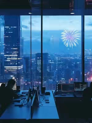 A nighttime cityscape viewed through a large window, with silhouettes of office workers at desks. Fireworks explode in the sky above the city. The overall color palette is cool blues and dark tones, creating a mood of celebration or festivity.