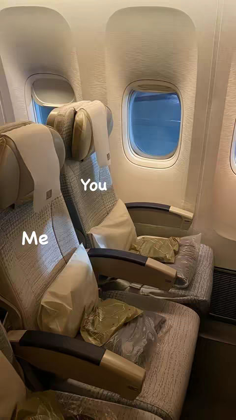 The cover image is taken inside an airplane. Two seats are visible, marked with the words 'Me' and 'You' in white text. The seats have beige leather with a pattern. There are windows in the background showing an obscured view outside. The overall lighting suggests the shot was taken at night.