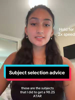 A young woman with long dark hair and wearing a black top is centered in a selfie-style video. Text overlays read 'Subject selection advice' in a black rectangle with teal borders and the following text in white 'these are the subjects that I did to get a 98.25 ATAR.' Also has a 'hold for 2x speed' text overlay near her ear