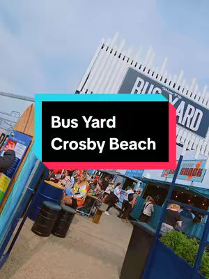 The cover image shows the entrance to a beach bar/restaurant with the name 'Bus Yard Crosby Beach' on a large sign. A hook in the center is highlighted. People are gathered in the background, at tables, appearing to enjoy a sunny day by the sea.