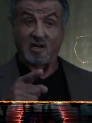 The cover image shows a close-up of Sylvester Stallone, gazing directly at the viewer and pointing with his right index finger. The background appears blurred and dark. A stylized reflection of orange and red light is at the bottom of the screen, giving the impression of light reflecting off water.