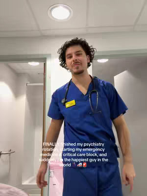 A man in a dark blue medical scrub stands in a brightly lit room with his hands down. Text is added to the lower part of the image.