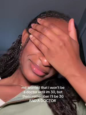A close-up shot of a light-skinned Black woman covering the top half of her face with her left hand, revealing the lower portion of her face. Her lips are slightly parted in a slight smile, and her eyes are partially visible beneath her fingers. She's wearing braids and hoop earrings. A text overlay is visible at the bottom.