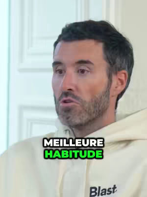 The image shows a man in a light-colored hoodie in a close-up shot. He is looking slightly to the side with a neutral expression. The upper portion of the image includes text overlays. Below the man is text, which is in a colored box.