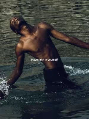 A man stands in water, torso visible, arms outstretched. The water's surface reflects light. Text across image.