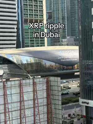 An urban scene dominated by skyscrapers, with the focus on a modern building that has a large ‘Ripple’ logo displayed on it. The sky is overcast. The overall shot is an exterior view of the city setting.