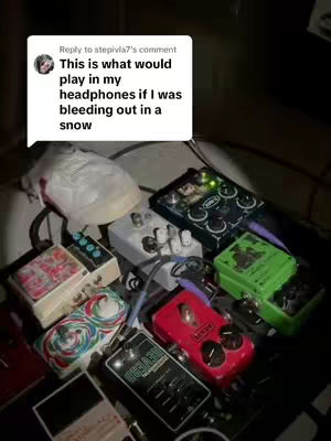 The image shows a collection of various guitar effect pedals and other electronic equipment, likely for a musical setup. The items are arranged on a dark surface with visible cables and connections. A comment bubble is placed on top, with the text overlay that reads: "This is what would play in my headphones if I was bleeding out in a snow". Visually, the image has a dark, indoor lighting setting with the gear's colors creating focal points..
