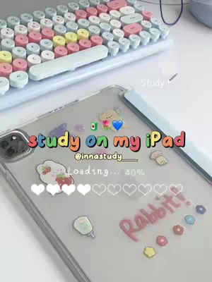 The image shows an iPad with a clear case covered in colorful stickers, including hearts, a blue heart, and the word 'Rabbit!'. A pastel keyboard sits in the background.