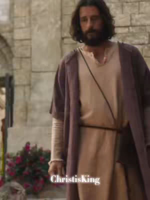 The cover image shows a man with long, dark hair and a beard wearing a beige robe with a purple overcoat, reminiscent of historical or biblical attire. He is standing near a structural wall, and the overall color palette is muted with natural tones. The image includes a hook at the bottom.