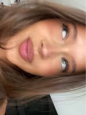 A close-up shot of a person's face, angled slightly from above. The focus is on the features. Visible are the eyes, with long lashes, and the full, pink lips, and the soft cheeks that are flushed with blush.
