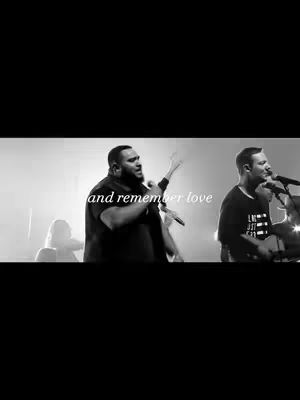 A grayscale image of a live music performance with three men on a stage with microphones. The image is well-lit, with stage lights illuminating the performers. The background is blurred lending focus to the singers. The text overlay states 'and remember love'.