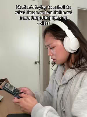 A young woman with dark hair wearing white headphones and a gray hoodie is angled to the right, looking down pensively. She is holding a calculator in her hands, and the background shows a partially visible door and wall.