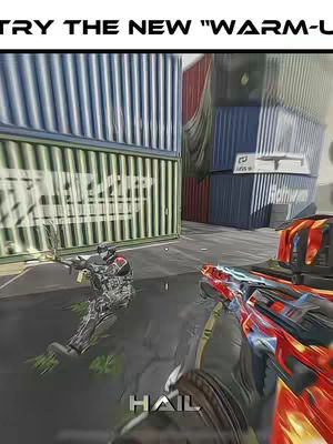 A first-person perspective from a video game. The scene shows a player aiming a weapon with another player in the background. The setting includes shipping containers and a grey ground.