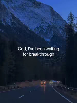 A scenic shot of a dark road leading towards a distant city, with mountains in the background under a twilight sky. The road and foreground are dark, contrasting with the lighter hues of the distant headlights. The text overlay reads: God, I've been waiting for breakthrough.