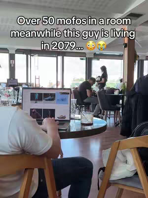 The cover image shows a person working on a laptop in a cafe setting. The laptop screen is displaying a webpage with several images. A hook is overlaid on top of the image, and other people can be seen in the background, also sitting in the cafe. The overall composition gives the impression of a modern workspace.