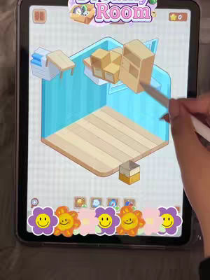 A tablet screen displaying an ASMR room design app. The interface shows a 3D room, with various furniture options floating in the air. A hand with a stylus is interacting with the screen.