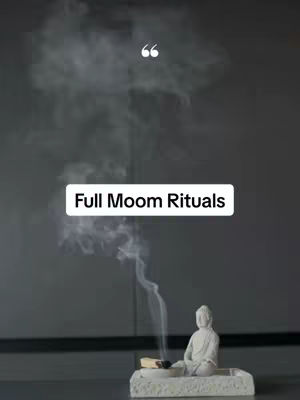 The image features a serene composition with a statue of a meditating Buddha on a white platform. Wisps of smoke rise from a lit incense stick placed on the platform. The background is a solid, dark gray color, creating a calm atmosphere.  The text overlay reads 'Full Moon Rituals'.